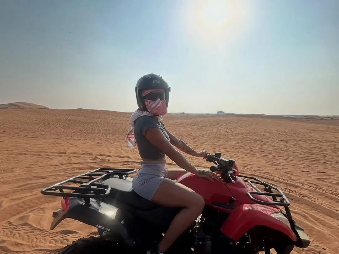 Rider on a quad bike under a strong midday sun in the Dubai desert