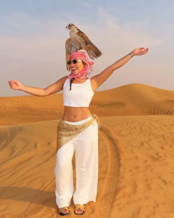 Smiling guest posing with a falcon perched on her head