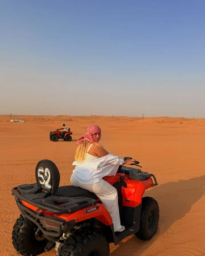 Rider on an orange quad bike looking back across the open desert