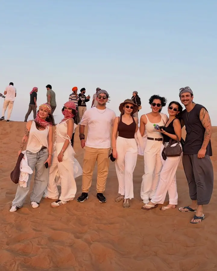 Group of friends smiling together on top of a sand dune