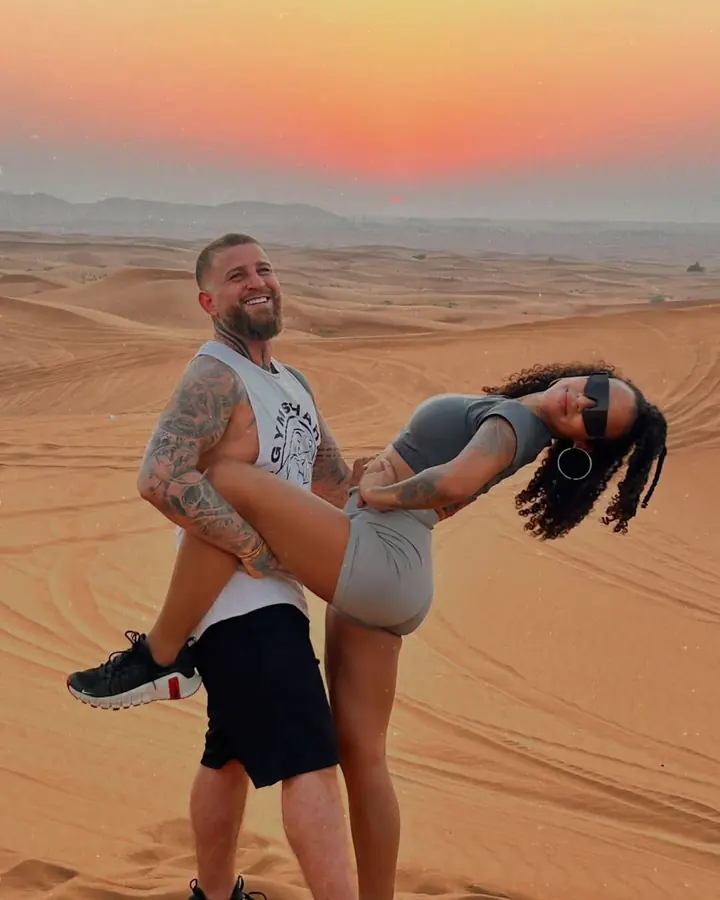 Couple posing playfully on the dunes with a pink sunset sky
