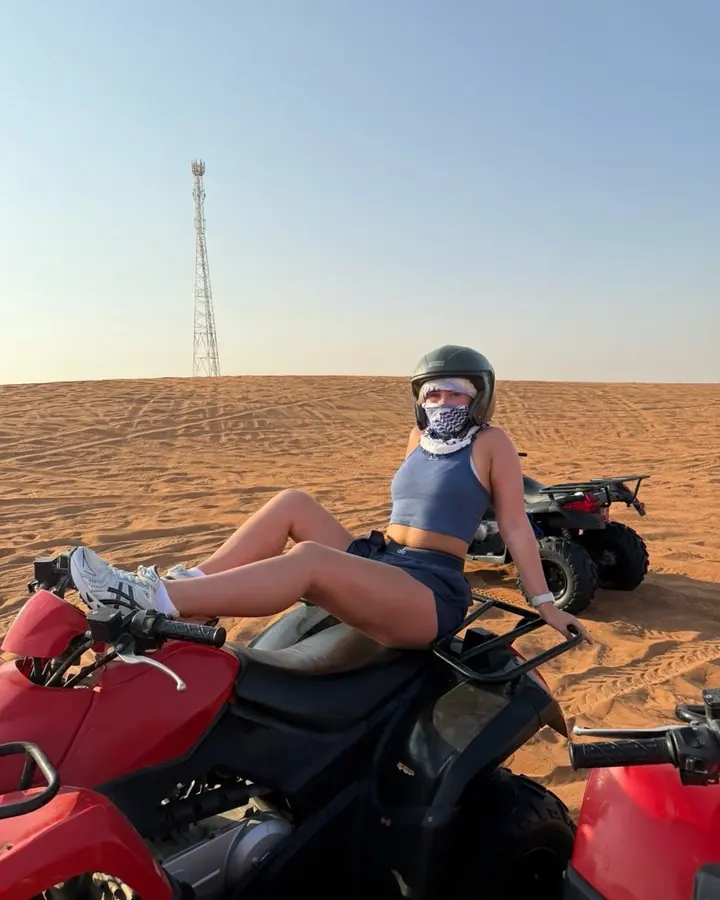 Rider in a helmet resting on a quad bike in the desert