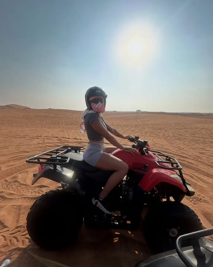 Rider in a helmet on a red quad bike under a bright sun