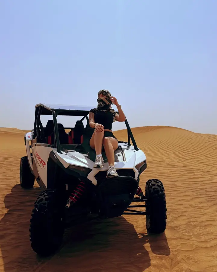 Guest sitting on top of a Polaris RZR dune buggy on the sand