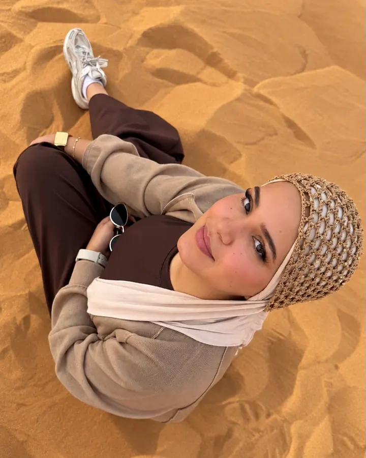 Smiling guest sitting on the red sand, photographed from above