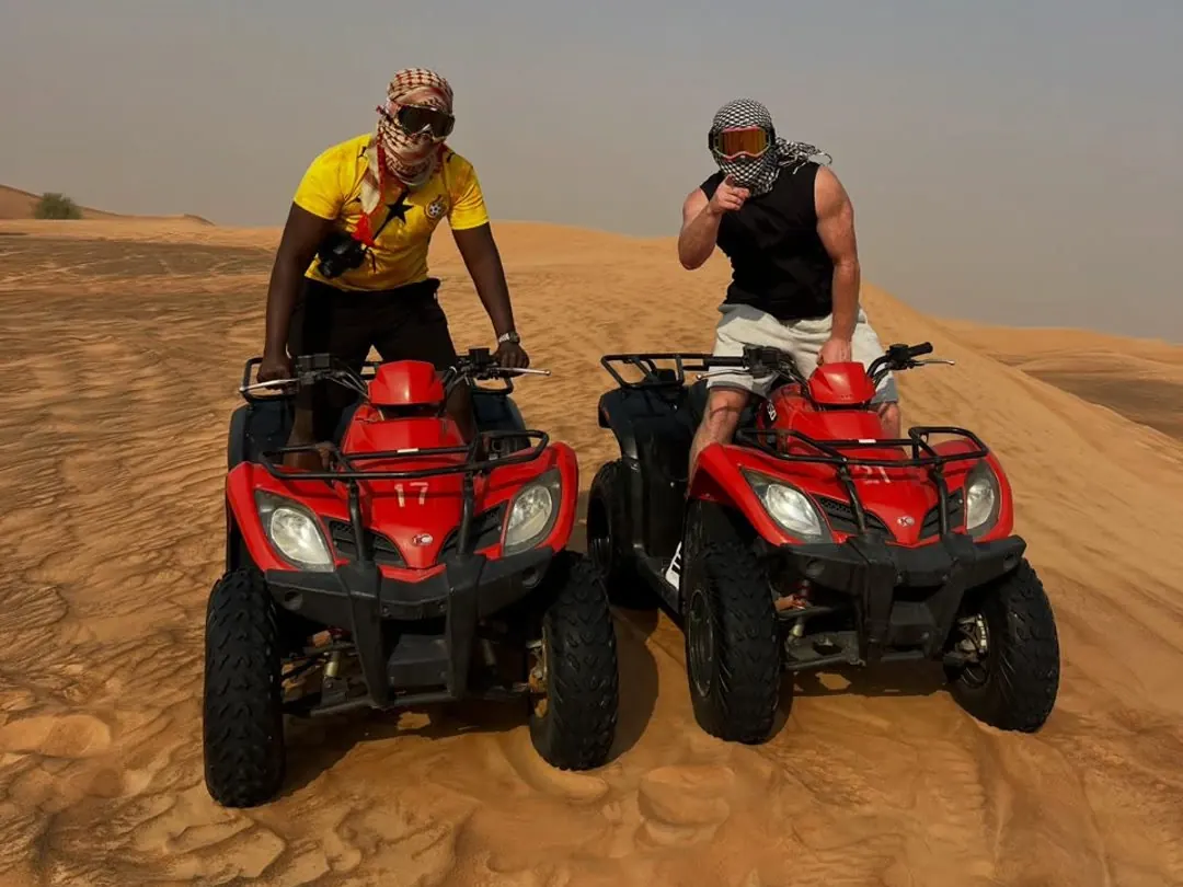 Two riders on red quad bikes on the dunes during a morning desert safari in Dubai