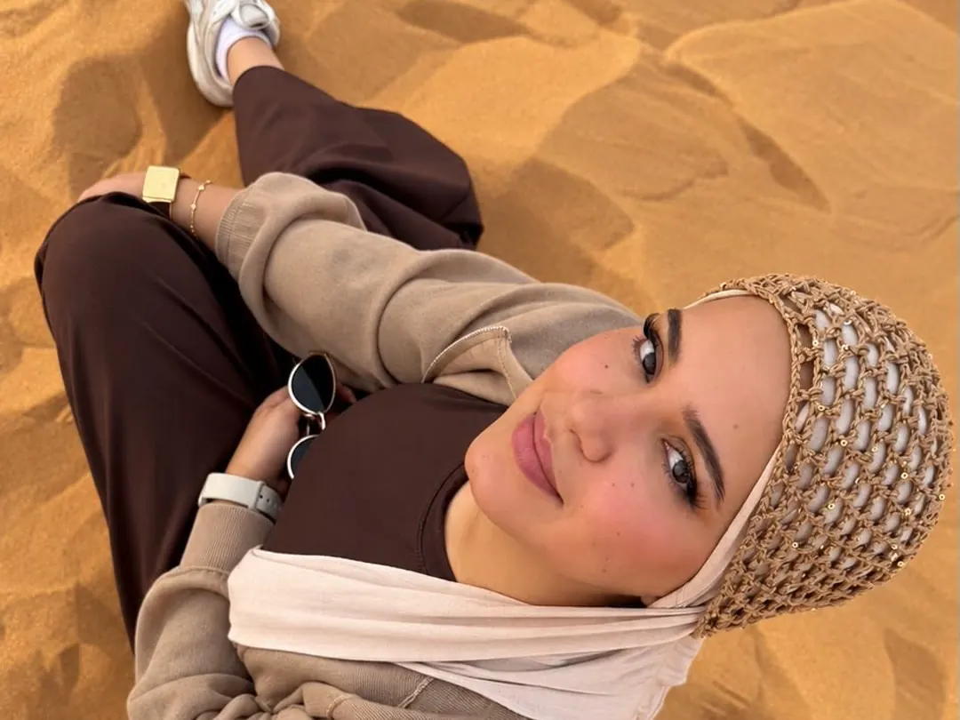 Smiling guest sitting on the red sand at a dune-top photo stop