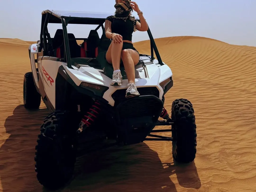 Guest sitting on a Polaris RZR dune buggy in the red dunes